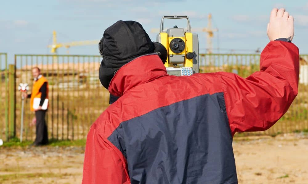 Licensed surveyor using total station equipment for a boundary line survey to verify property lot size