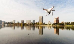 Drone surveying a riverfront with city buildings in the background
