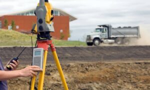 Surveyor using equipment on a construction site to conduct a flood elevation survey for site planning