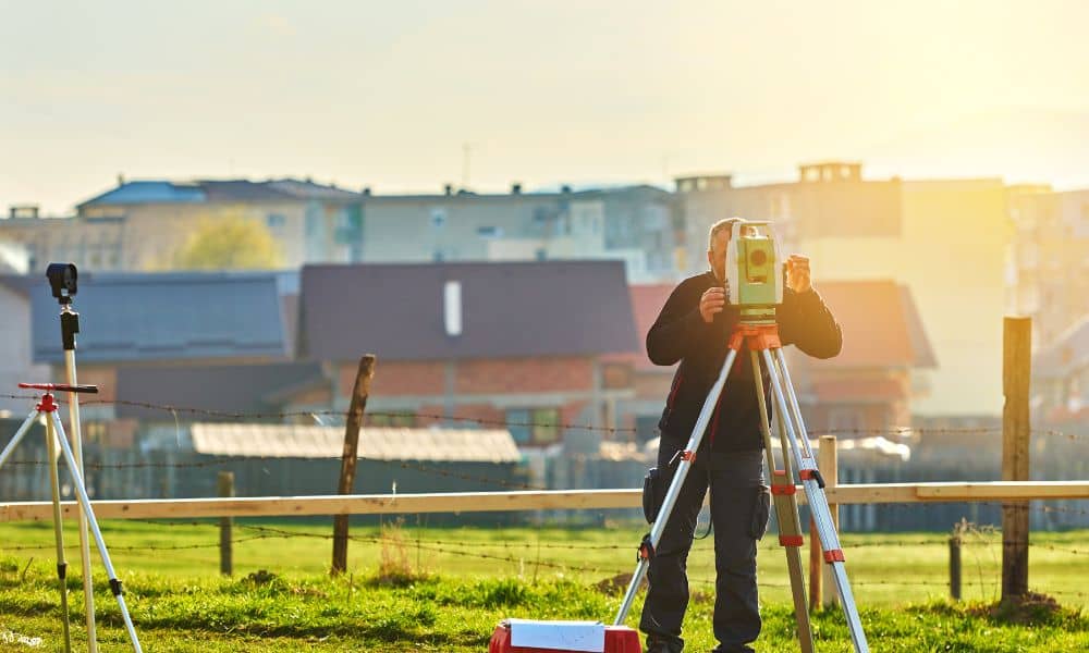 Surveyor measuring residential lot lines with a total station during a boundary survey