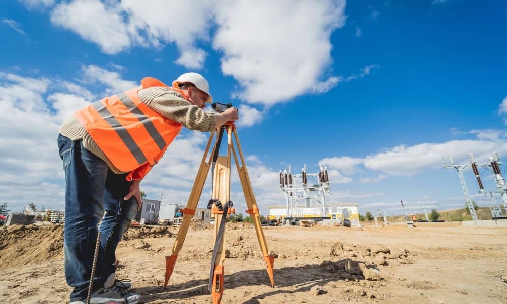 A surveyor using a total station to check land surveying details and spot issues that could affect a property project