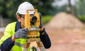 A construction survey being performed by a surveyor using a total station on an active job site