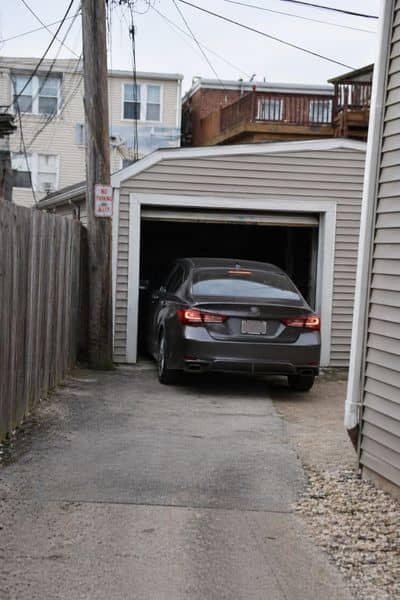 Car turning into a narrow alley garage with very limited space between homes on a tight city lot