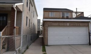 Narrow urban lot with houses close together and a rear alley garage, showing tight spacing and limited side yard common in city homes