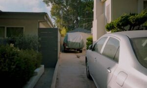 A narrow driveway between neighboring homes, with parked cars illustrating the parking and access details a loan closing survey can document before a home purchase
